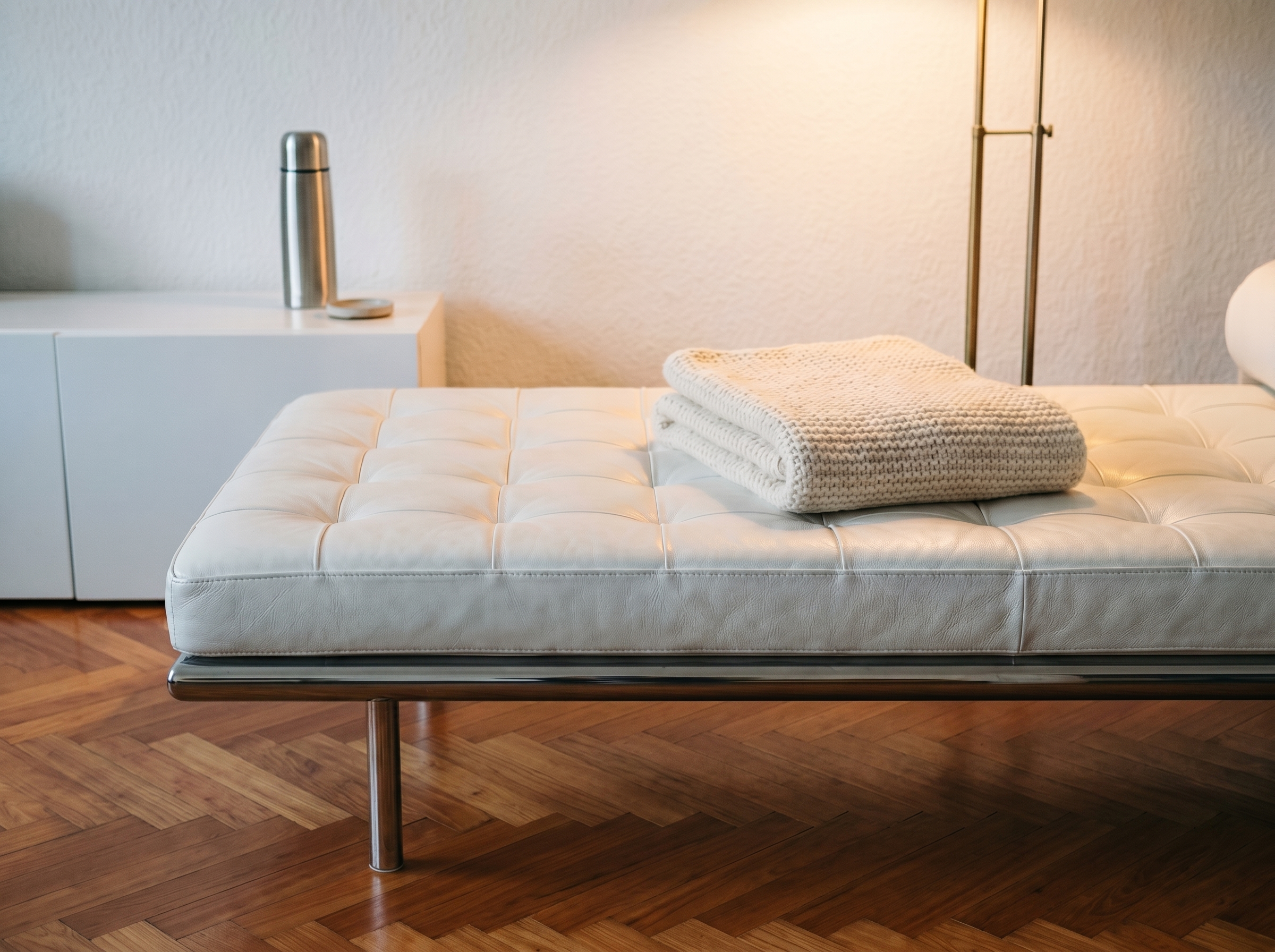Die Daybed im Sprechzimmer: weisses getuftetes Leder auf Chromrahmen, Fischgrät-Parkett